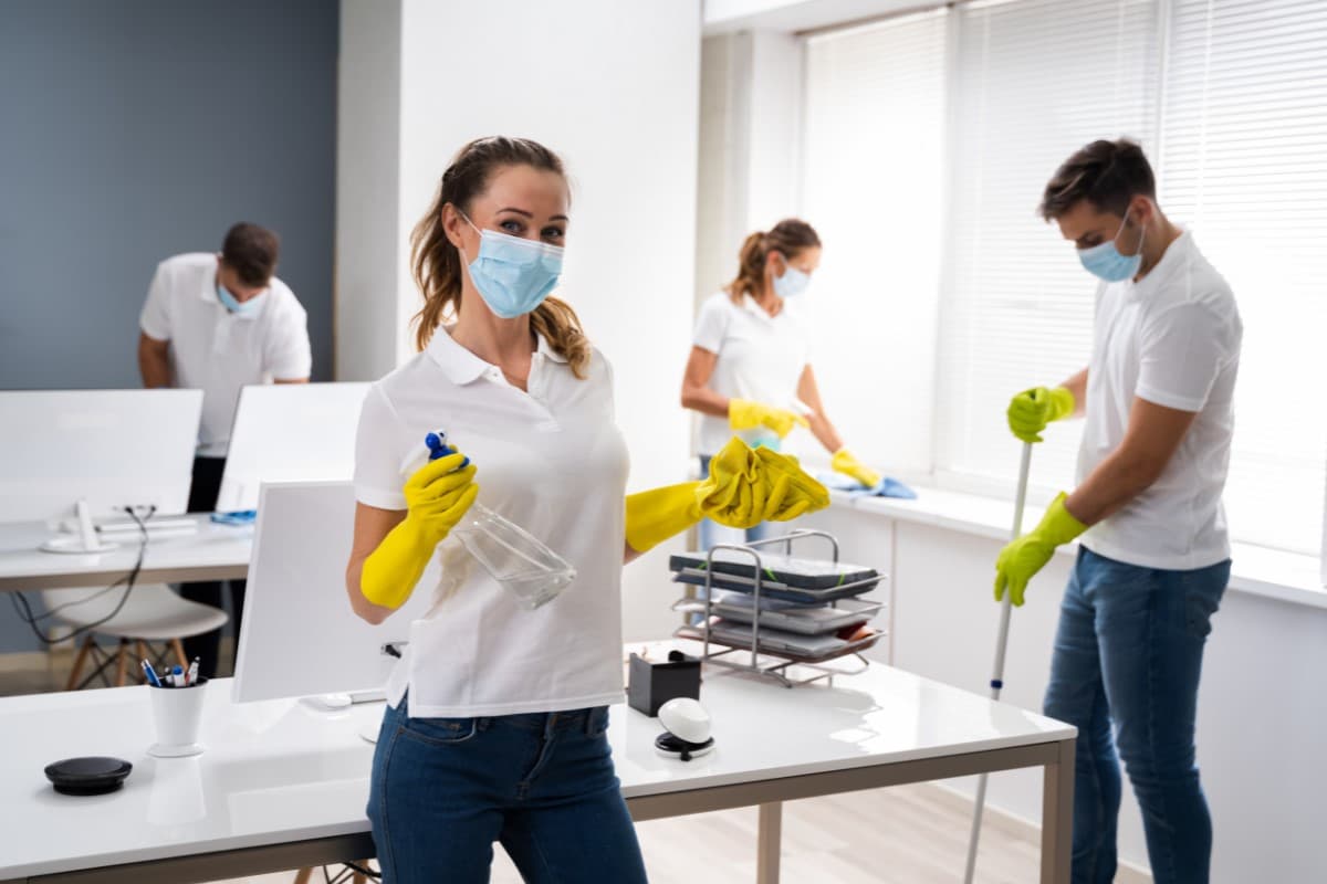 Image of a cleaning team diligently cleaning the windows, floor, and furniture in a commercial office.